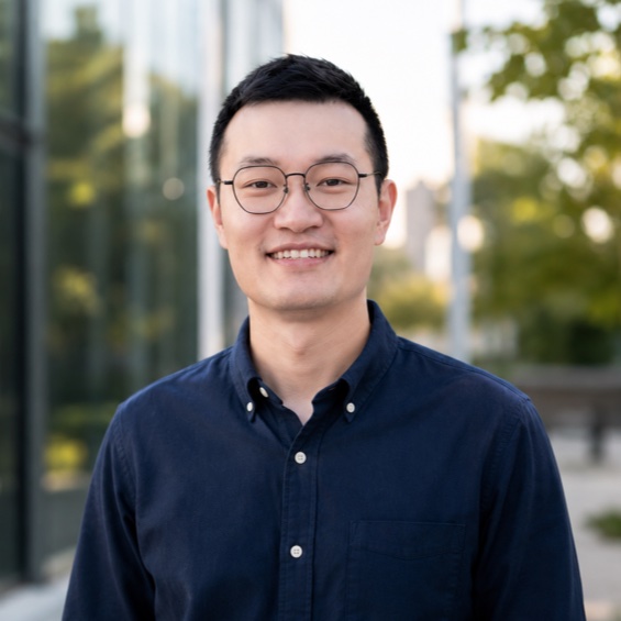 Terence Tao, smiling in a navy shirt outside a glass building